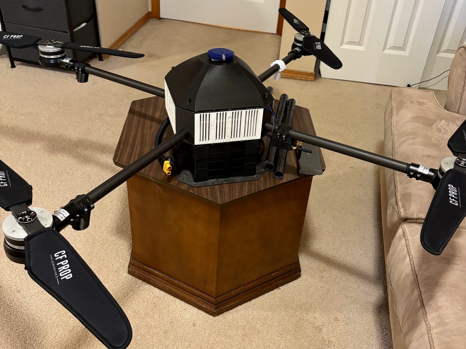 The assembled carbon-fiber X-frame quadcopter: four carbon arms with folding props, the printed centre body, and the GPS mast
